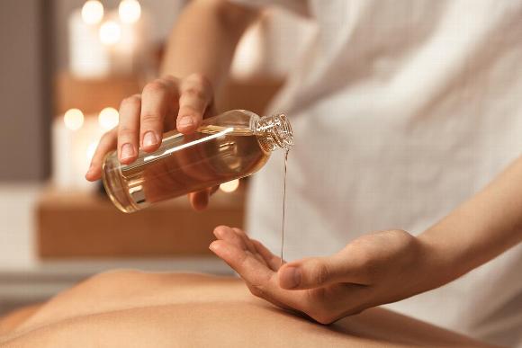 Masseuse pouring almond oil